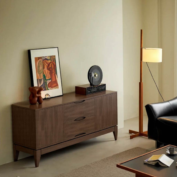 A stylish living room corner featuring a wooden cabinet, framed art, a vinyl record player, a floor lamp, and a black armchair.