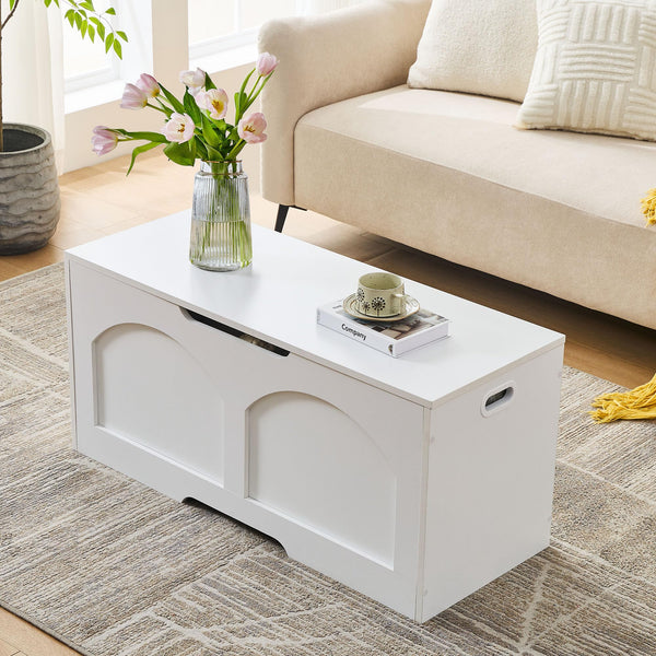 A bright living room featuring a white coffee table with a vase of tulips, a tea set, and a book, alongside a beige sofa.