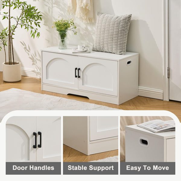 Modern white storage cabinet with arched doors, black handles, and a textured cushion on top, set in a bright room with plants.