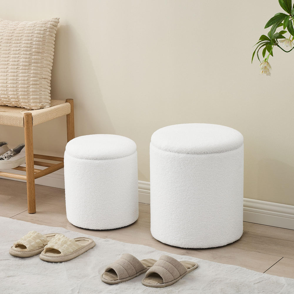 Two white, fluffy storage ottomans sit on a soft carpet, one open with books and a yellow throw inside, enhancing a cozy interior.