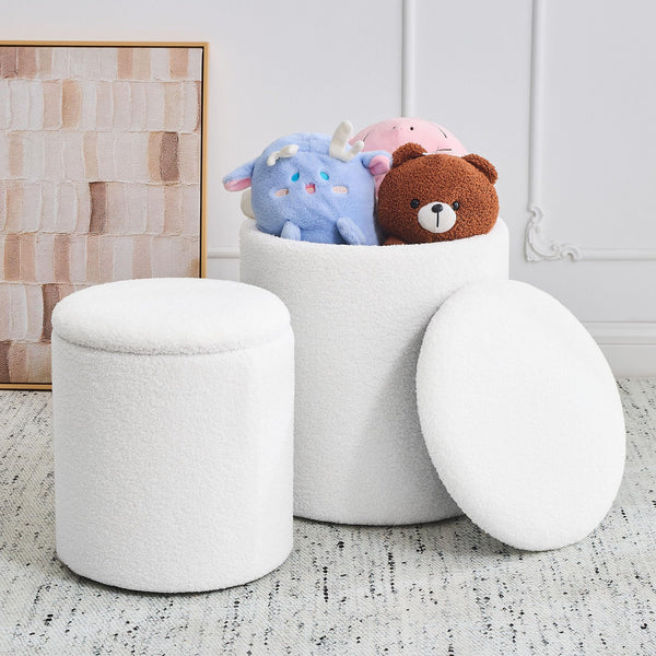 Two white, fluffy storage ottomans sit on a rug, one open with plush toys peeking out, alongside a framed abstract artwork.