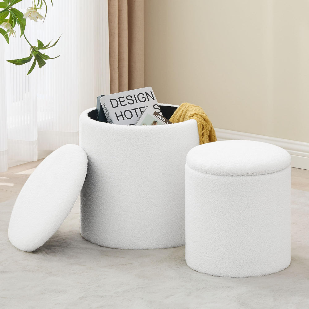 Two white, fluffy storage ottomans sit on a soft carpet, one open with books and a yellow throw inside, enhancing a cozy interior.
