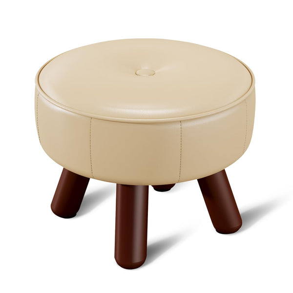 A round beige leather ottoman with a button-tufted top and sturdy wooden brown legs. Ideal for seating or decor.