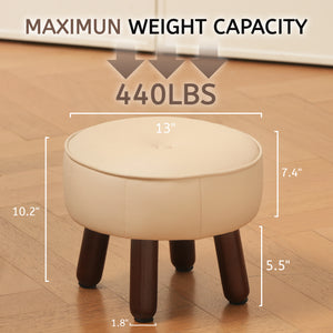 A cream-colored ottoman with dimensions and a maximum weight capacity of 440 lbs, resting on four dark wooden legs on a wood floor.