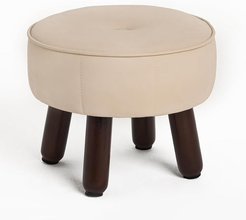 A round beige ottoman with a tufted top, featuring dark wooden legs and a sleek, modern design.